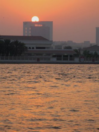 Sun setting behind arched building on Dubai Creek Sun setting behind arched building on Dubai Creek