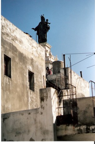 Girl on mobile phone at feet of Holy Mother in Havana