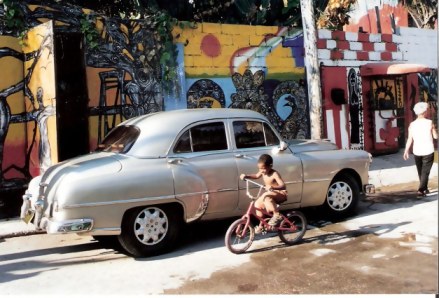 Havana-Classic-car-against-mural-covered-walls-in-Barrrio-Cayo-Hueso 